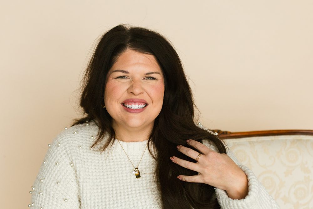 Liz Rodriguez laughing, seated on a cream settee